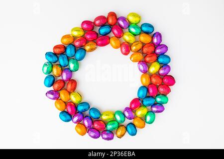Colourful Easter sweets in a circle, chocolate eggs on a white background, copying space in the middle Stock Photo