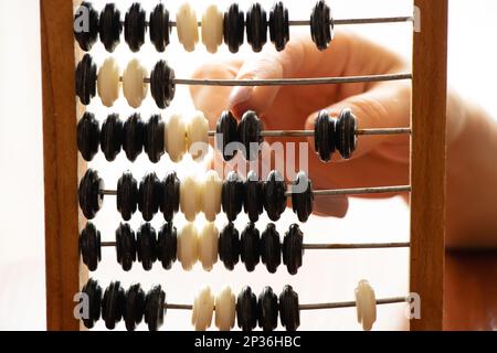 Old wooden abacus for counting money and a woman's hand on a bright light Stock Photo