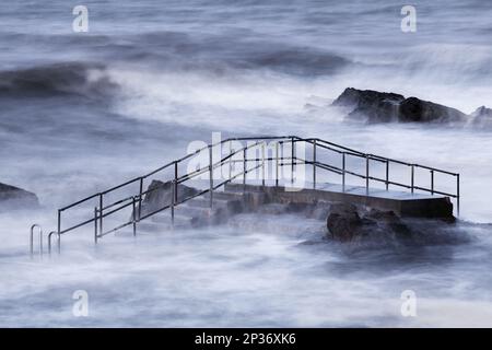 Tidal pool steps above breaking waves during incoming tide on windy morning, Bude Sea Pool, Summerleaze, Bude, Cornwall, England, United Kingdom Stock Photo