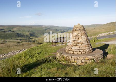 Cairn and bench at highland viewpoint overlooking valley marking Muker parish boundary, Millennium Cairn, Buttertubs Pass, Swaledale, Yorkshire Dales Stock Photo