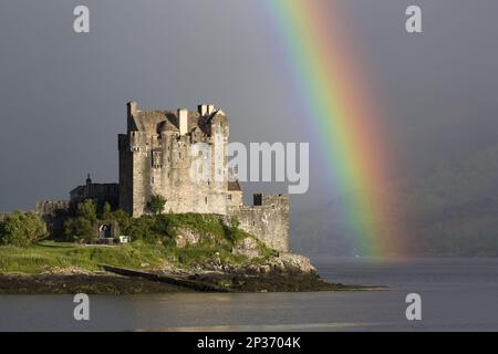 View of restored castle on tidal island in sea loch with rainbow, in evening sunlight, Eilean Donan Castle, Loch Duich, Ross and Cromarty, Highlands Stock Photo