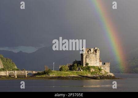 View of restored castle on tidal island in sea loch with rainbow, in evening sunlight, Eilean Donan Castle, Loch Duich, Ross and Cromarty, Highlands Stock Photo