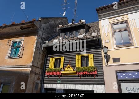 Town of Skofja Loka in Slovenia, unique house on Spodnji trg 37 with traditional wooden facade, decorated with dwarfs figurines, windows with yellow s Stock Photo