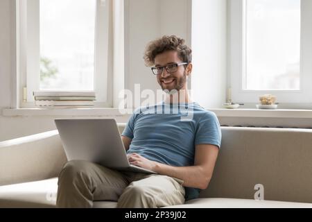 Positive successful handsome freelance business man sitting on sofa Stock Photo