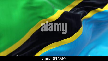 Close-up view of the Tanzania national flag waving. Green and blue triangles with black diagonal stripe and yellow edges. Fabric textured background. Stock Photo