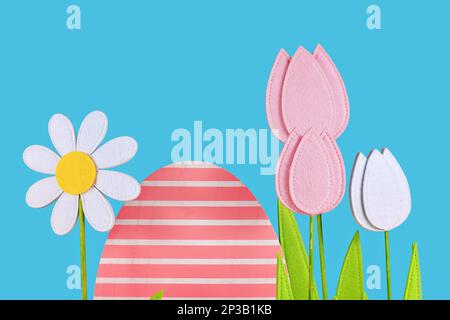 Felt tulip and daisy spring flowers and easter egg on blue background with copy space Stock Photo