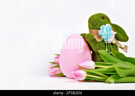 Grass Easter bunny, tulip flowers and painted eggs with copy space Stock Photo