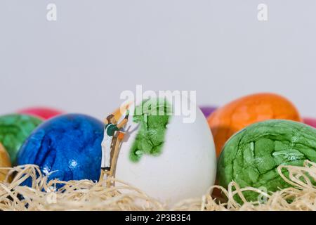 painter on a wooden ladder in an easter basket paints an egg green Stock Photo