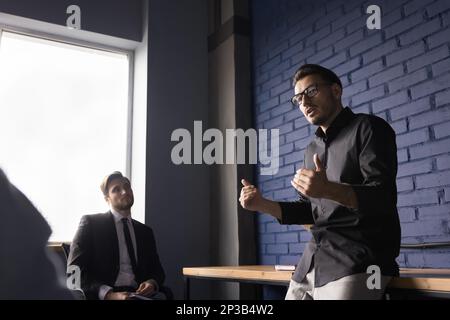Serious stylish male coach giving workshop to group of employees Stock Photo