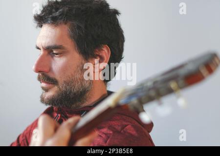 close-up of a bearded man playing the Spanish guitar concentrating on music Stock Photo