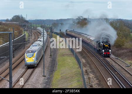 Steam train '34046 Braunton' pulling the 'Golden Arrow' through Kent is passed by its modern day equivalent, a Eurostar, on route to London. Stock Photo