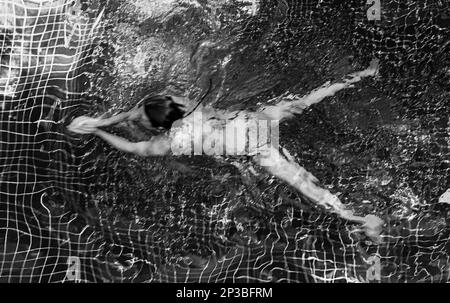 An abstract view of a woman swimming in a pool in Siem Reap in Cambodia. Stock Photo
