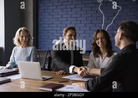 Happy confident business partner men shaking hands over meeting table Stock Photo