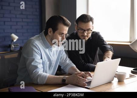 Two focused business partners men working at laptop together Stock Photo