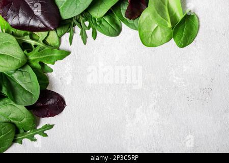 Frame from salad mix leaves, arugula, spinach, chard on a gray background. Place for text. Stock Photo