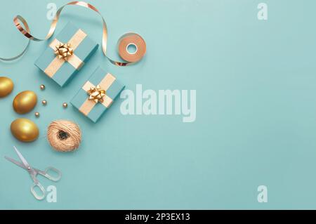 Top view of easter gift boxes wrapped in gold with gold eggs, and wrapping accessories Stock Photo