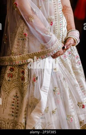 A newlywed Indian bride with nice henna  tattoo design wearing a white bridal dress Stock Photo