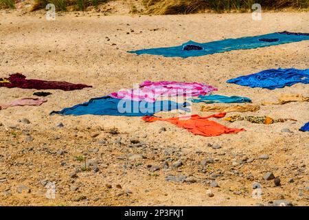 Tuareg  women dry washed clothers in traditional way. Colorful laundry drying in the sun on sand. Tassili n'Ajjer National Park, Algeria, Sahara, Afri Stock Photo