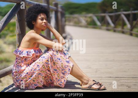 Thoughtful black woman sitting on boardwalk Stock Photo