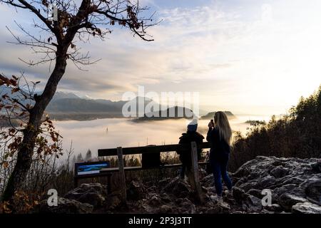 2022 12 30, Bled, Slovenia: Two women looking over a completely fog covered Lake Bled, one taking a picture Stock Photo