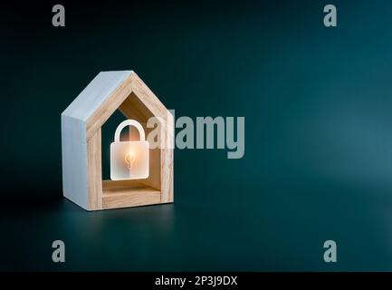 Digital lock icon glowing in simple miniature wooden house isolated on green background with copy space. Smart Home security, home insurance, real est Stock Photo