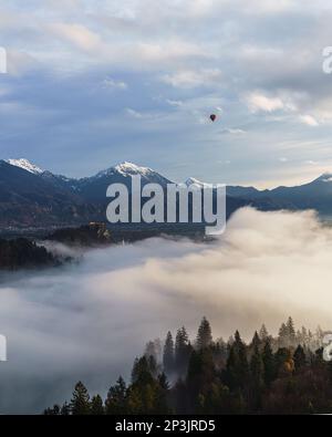 2022 12 30, Bled, Slovenia: Lake Bled, covered in Fog, with a Hot Air Balloon hanging in the sky above Stock Photo