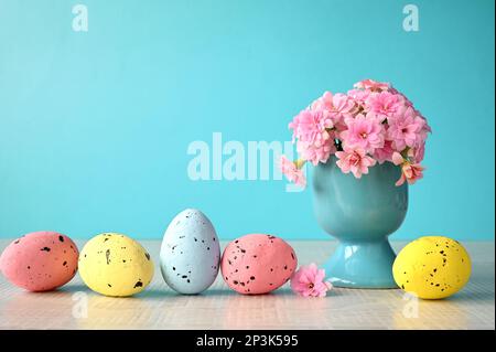 Vase of flowers and easter eggs on a blue background with space for text. Stock Photo