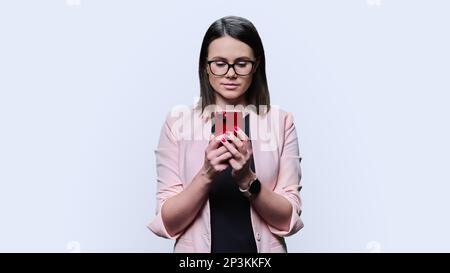 Young business woman using smartphone on white studio background Stock Photo