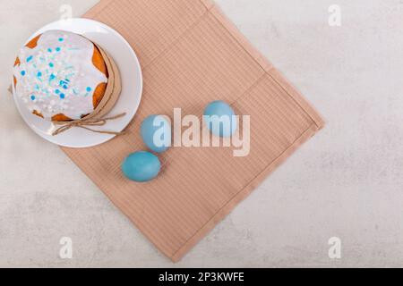Easter russian cake and colorful eggs on a napkin, on light table. Happy easter poster and banner for greeting text. Top view Stock Photo