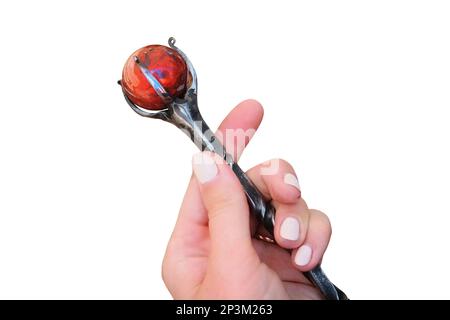 In women's hands a large hairpin in the form of a staff of Jasper, isolated on a white background. Fantasy hair pin with a big stone. Stock Photo