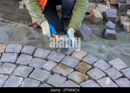 Worker were using industrial cobblestones to pave sidewalk with granite stones. Stock Photo
