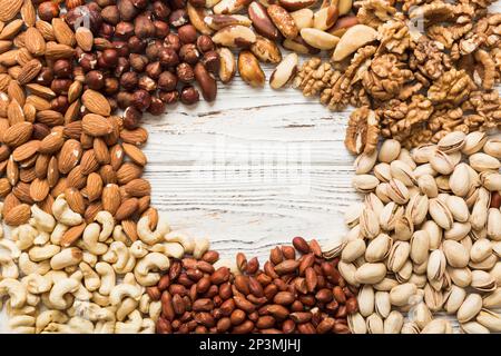 different nuts frame background. Close up, top view, flat lay with vopy space. Walnut, pistachios, almonds, hazelnuts and cashews. Stock Photo