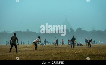 Kolkata, India - January 15, 2023: Local boys playing an unorganized cricket match in a misty winter morning. Shallow depth of field. Stock Photo