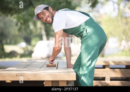 happy man painting wooden fence outdoors Stock Photo
