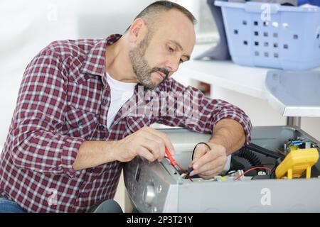 serviceman testing washing machine with multimeter Stock Photo