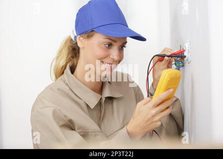female electrician testing socket using a multimeter Stock Photo