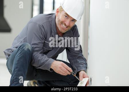 portrait of mature male electrician installing socket Stock Photo