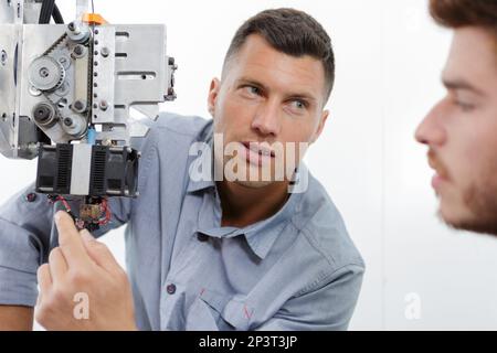 two mechanics repairing modern laser cutting machine in workshop Stock Photo