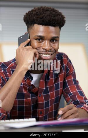 man sat at his desk talking on a smartphone Stock Photo