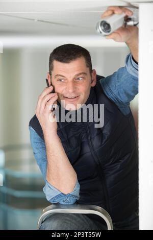 technician installing cctv camera on ceiling indoors Stock Photo