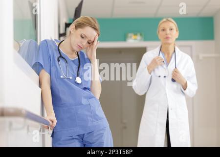 female nurse with a headache resting in hospital corridor Stock Photo
