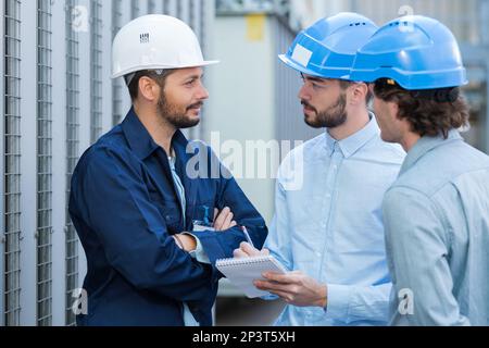three engineers checking plans with documents at construction site Stock Photo