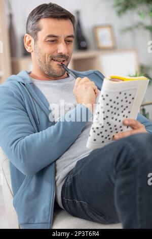 young man sitting doing a crossword puzzle Stock Photo