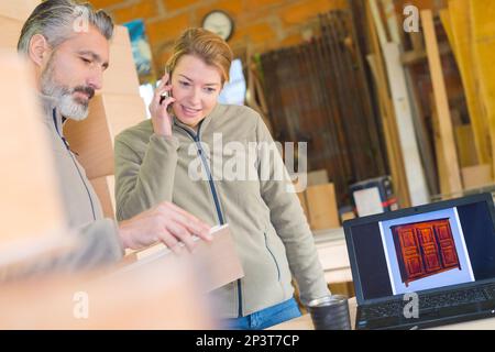 female worker using telephone in cabinet makers workshop Stock Photo