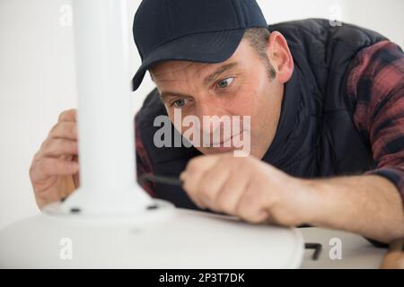 concentrated man in fixing a chair Stock Photo