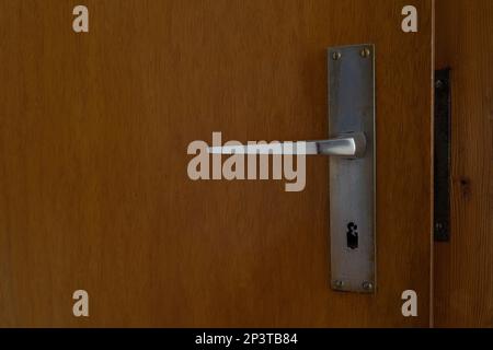 Old used door handle on a brown wooden door in a apartment Stock Photo