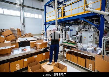 Worker packing coffee packages into cardboard boxes. Stock Photo