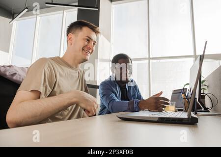 Two smiling positive programmers working in the office of a software development company. Coding technologies, site design. Successful diverse Stock Photo