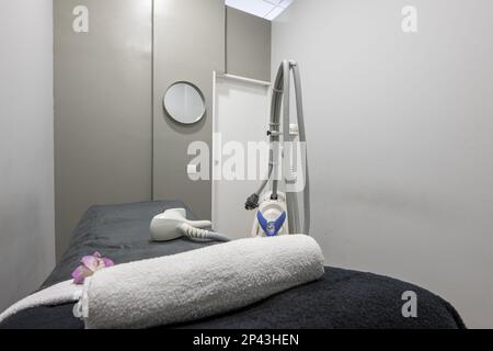 Aesthetic medicine treatment cabin with a stretcher with a blanket, electric devices to apply treatments and creams, towels and mirrors Stock Photo
