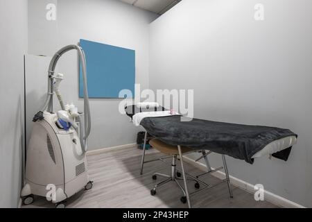 Aesthetic medicine treatment cabin with a table with a blanket, mobile electric devices with wheels to apply treatments and creams, towels and mirrors Stock Photo